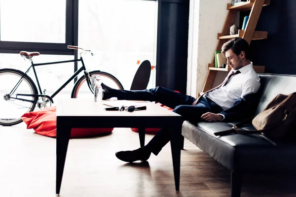 Человек в костюме спит на диване после вечеринки в офисе — стоковое фото