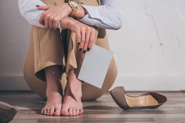 Vista cortada da mulher sentada no chão, segurando foto perto de sapatos e parede branca em casa, conceito de transtorno de luto — Fotografia de Stock