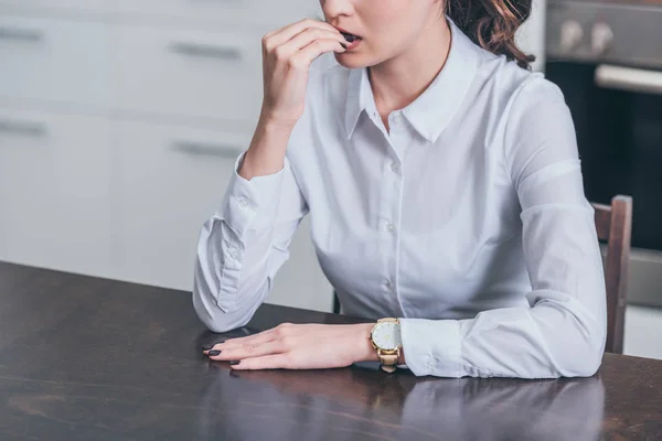 Cropped view of sad woman in white blouse sitting by table in kitchen, grieving disorder concept — Stock Photo