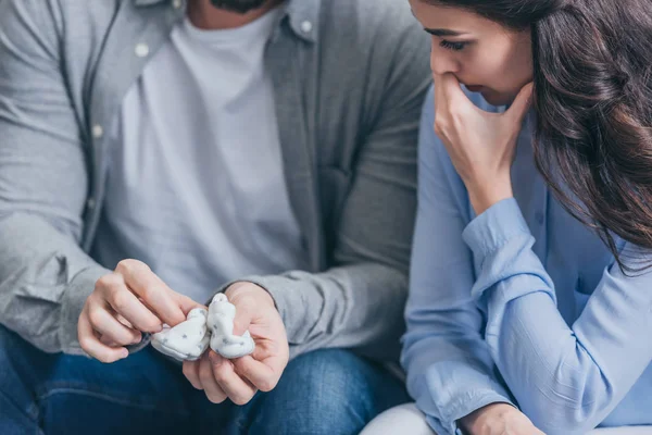 Cropped view of crying woman and man holding baby socks at home, grieving disorder concept — Stock Photo