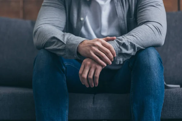 Abgeschnittene Ansicht eines Mannes, der zu Hause auf dem Sofa sitzt — Stockfoto