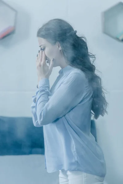 Selective focus of depressed woman covering face with hands and crying at home — Stock Photo