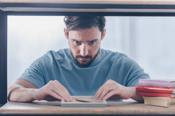 Enfoque selectivo de hombre molesto guapo sosteniendo el marco de la foto en casa - foto de stock