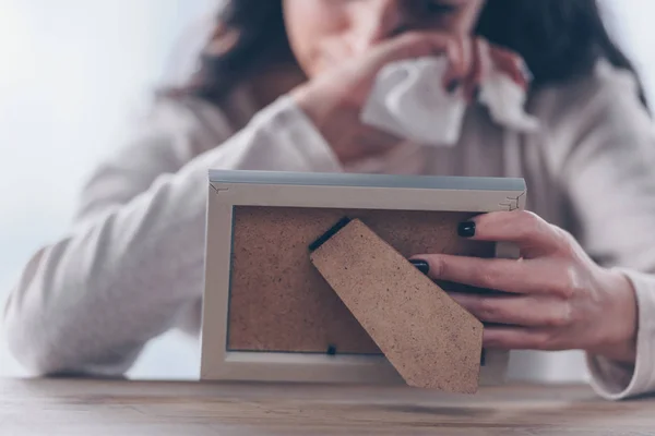 Cropped view of upset woman holding picture frame and crying at home — Stock Photo