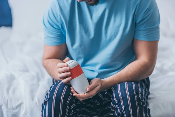 Cropped view of man sitting on bed and holding funeral urn — Stock Photo