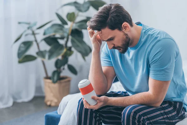 Selective focus of stressed man touching head and looking at funeral urn — Stock Photo