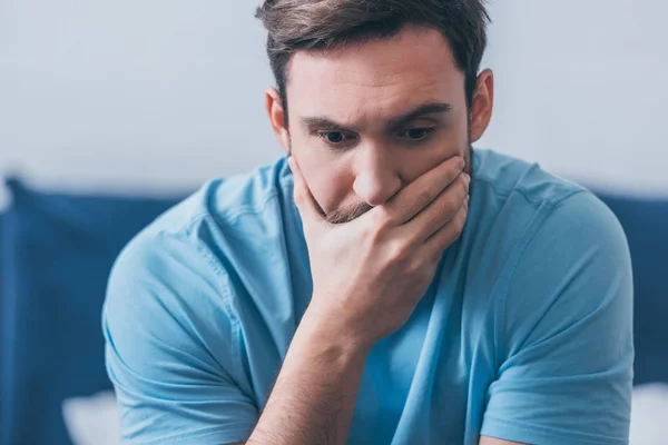 Enfoque selectivo del hombre estresado que cubre la boca con la mano en casa - foto de stock