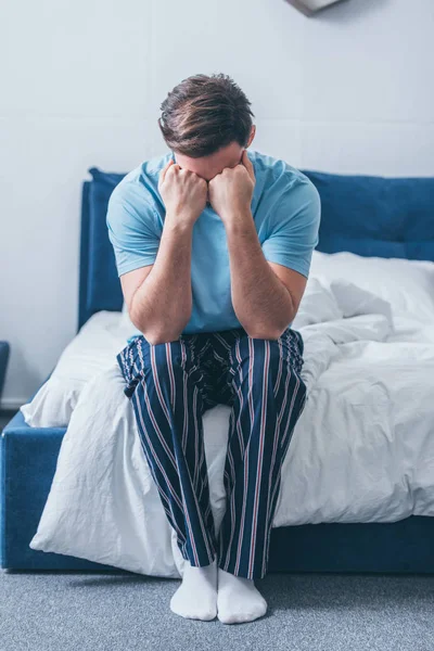 Trauernder Mann sitzt auf Bett, bedeckt Gesicht mit Händen und weint zu Hause — Stockfoto