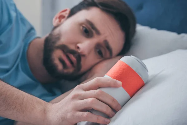 Grieving man lying in bed and holding funeral urn — Stock Photo