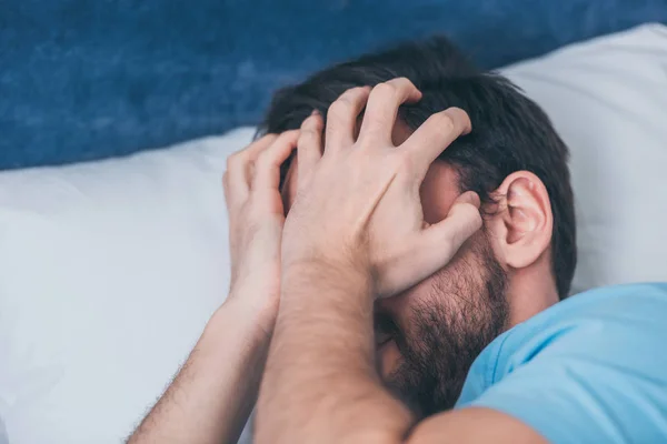 Uomo in lutto sdraiato a letto, che copre il viso con le mani e piange a casa — Foto stock