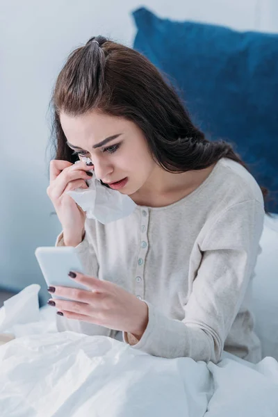 Schöne traurige Frau liegt im Bett, weint und benutzt Smartphone — Stockfoto