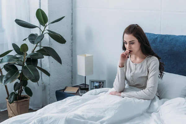 Schöne depressive Frau liegt im Bett und beißt Finger — Stockfoto