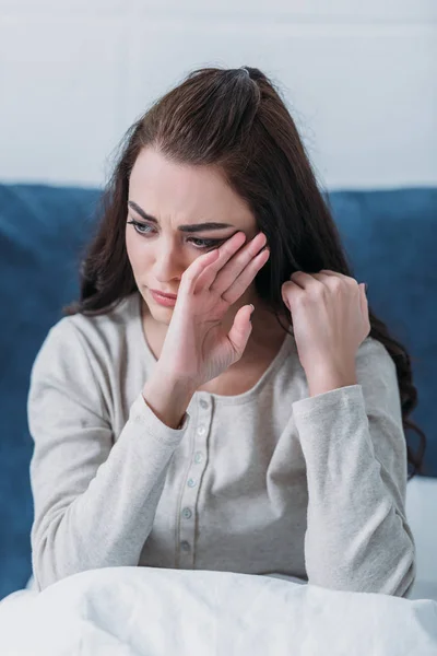 Depressed woman crying and wiping tears while lying in bed at home — Stock Photo