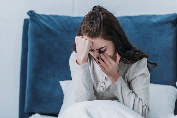 Depressed woman crying and wiping tears while lying in bed at home — Stock Photo