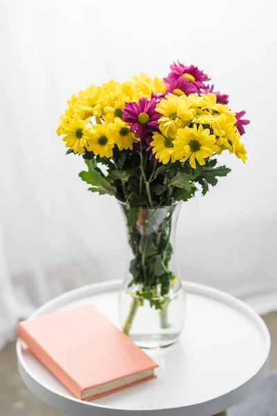 Flores frescas y libro sobre mesa blanca - foto de stock