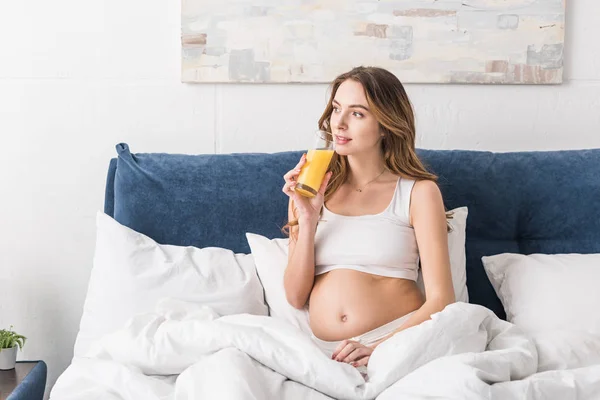 Mulher grávida sonhadora beber suco na cama — Fotografia de Stock