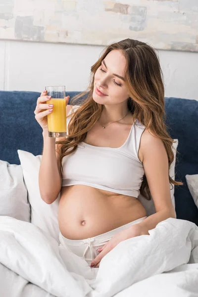 Mulher grávida despreocupada beber suco na cama — Fotografia de Stock