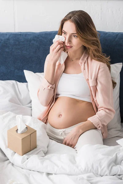 Triste embarazada joven limpiando lágrimas con servilleta - foto de stock