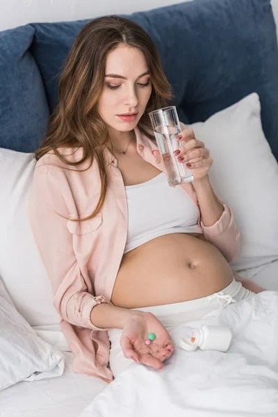 Pregnant woman holding pills and drinking water — Stock Photo