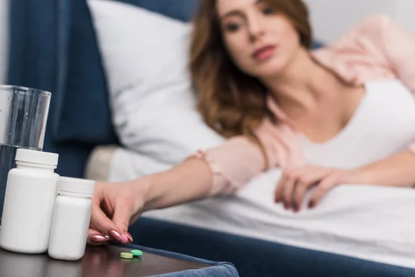 Ausgeschnittene Ansicht einer Frau im Bett, die Medikamente nimmt — Stockfoto