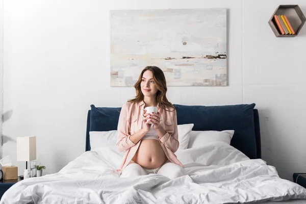 Рад, что беременная женщина пьет кофе в постели утром — стоковое фото