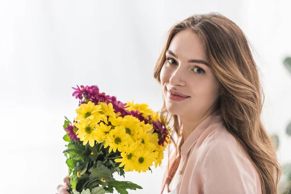 Atractiva joven mujer con flores mirando a la cámara - foto de stock