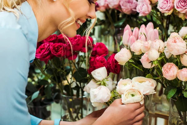 Обрезанный вид улыбающейся женщины, выбирающей цветы в цветочном магазине — стоковое фото
