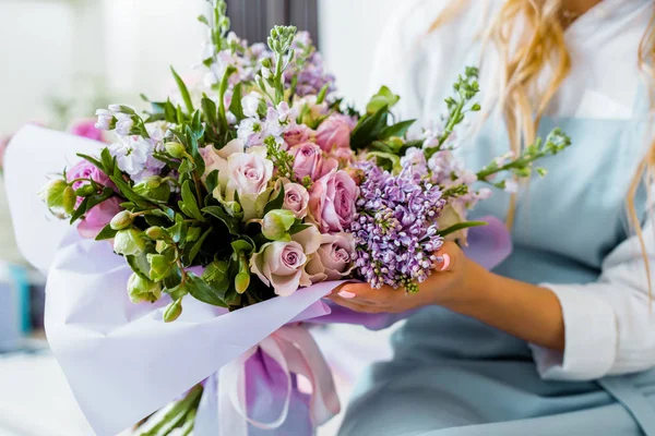 Vista recortada de floristería femenina sosteniendo ramo con lila y rosas en floristería — Stock Photo