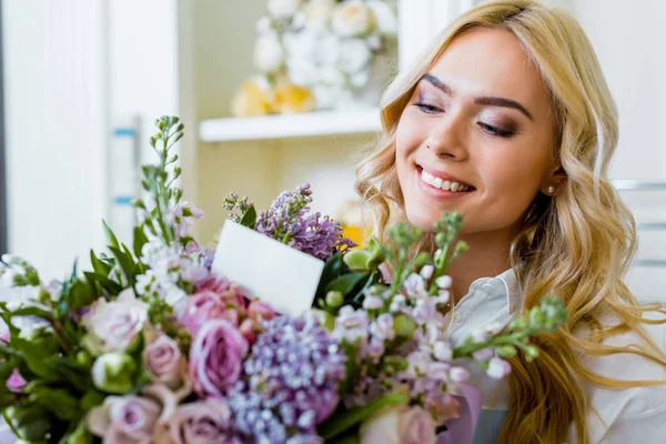 Bela mulher sorridente segurando buquê de flores com rosas, lilás e cartão com espaço de cópia — Fotografia de Stock