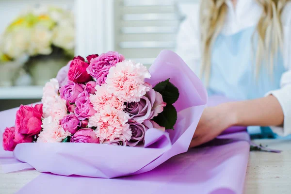 Cropped view of female florist arranging bouquet with pink roses and carnations — Stock Photo