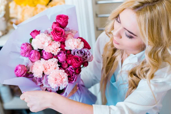 Beautiful blonde woman holding flower bouquet with roses and carnations in flower shop — Stock Photo
