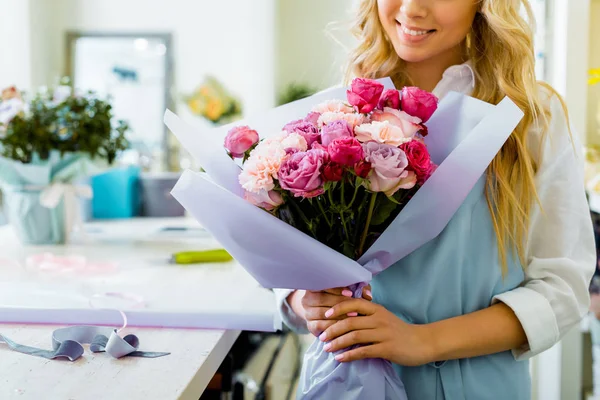 Частковий вид на жіночого флориста, що тримає букет з трояндами та гвоздиками в квітковому магазині — стокове фото