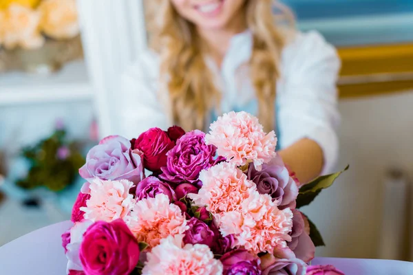 Частичный взгляд женщины, держащей цветочный букет с розами и гвоздиками — стоковое фото