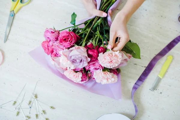 Partial view of female florist arranging bouquet with pink roses and carnations — Stock Photo