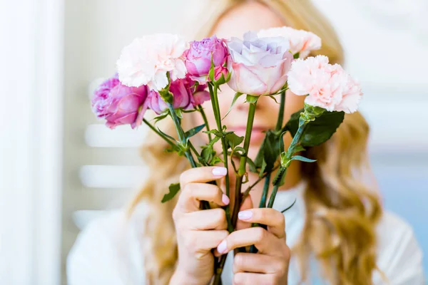 Femme tenant des roses roses et des œillets devant le visage — Photo de stock