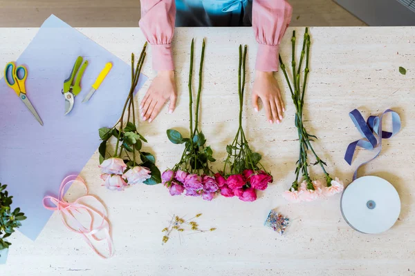 Vista ritagliata di fiorista donna al banco con forniture decorative, fiori e strumenti nel negozio di fiori — Foto stock