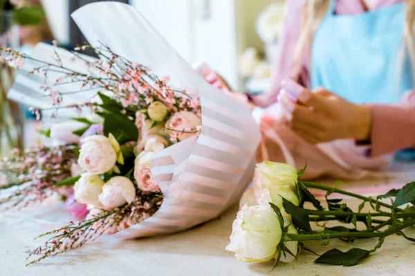 Visão parcial do florista feminino que envolve buquê de flores com rosas em papel — Fotografia de Stock