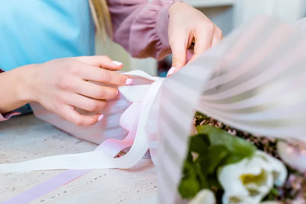 Partial view of female florist wrapping flower bouquet in paper — Stock Photo