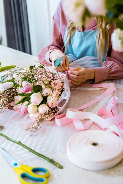 Teilansicht einer Blumenhändlerin, die einen Strauß Rosen im Blumenladen arrangiert — Stockfoto