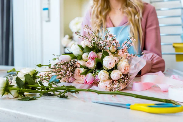 Partial view of female florist arranging bouquet of roses in flower shop — Stock Photo