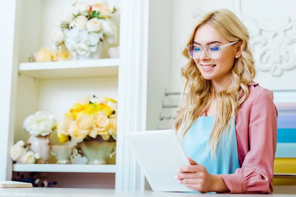 Вибірковий фокус власник магазину красиву квітку жінка в окулярах, використовуючи цифровий планшетний — стокове фото