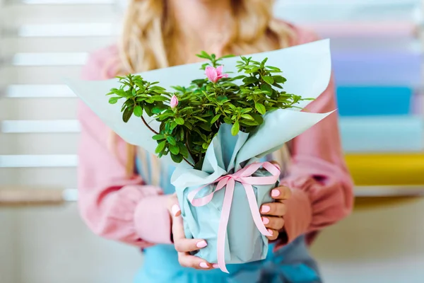 Vista cortada da mulher segurando buquê de flores com papel de embrulho e fita rosa — Fotografia de Stock