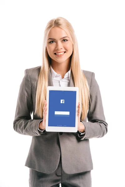 Hermosa mujer de negocios rubia mostrando tableta digital con aplicación de facebook en la pantalla, aislado en blanco - foto de stock