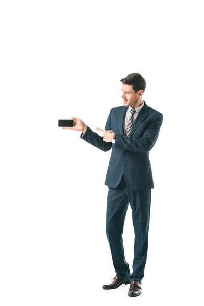 Uomo d'affari in giacca e cravatta che punta a schermo bianco su smartphone, isolato su bianco — Foto stock