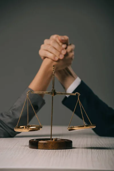 Selektive Fokussierung von Geschäftskollegen auf Holztisch mit Gerechtigkeitswaage auf Grau — Stockfoto
