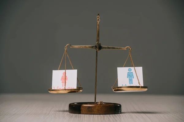 Símbolos masculinos y femeninos en escamas sobre mesa de madera sobre gris, concepto de igualdad de género - foto de stock