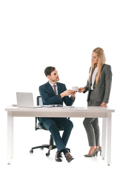 Belle secrétaire féminine apporté tasse de café pour homme d'affaires sur le lieu de travail avec ordinateur portable, isolé sur blanc — Photo de stock