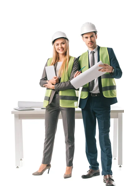 Architects in safety vests and hardhats holding digital tablet and blueprint, isolated on white — Stock Photo