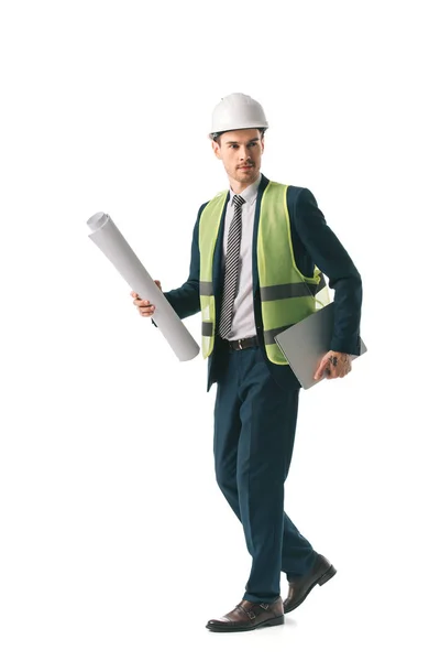 Male architect in hardhat and safety vest walking with blueprint and laptop, isolated on white — Stock Photo