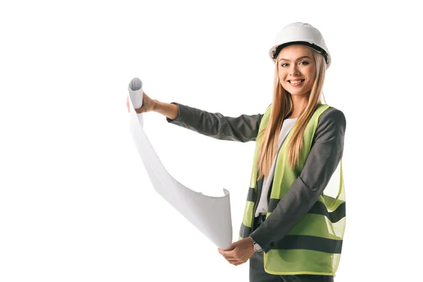 Sonriente arquitecta en chaleco de seguridad y casco sosteniendo plano, aislada en blanco - foto de stock